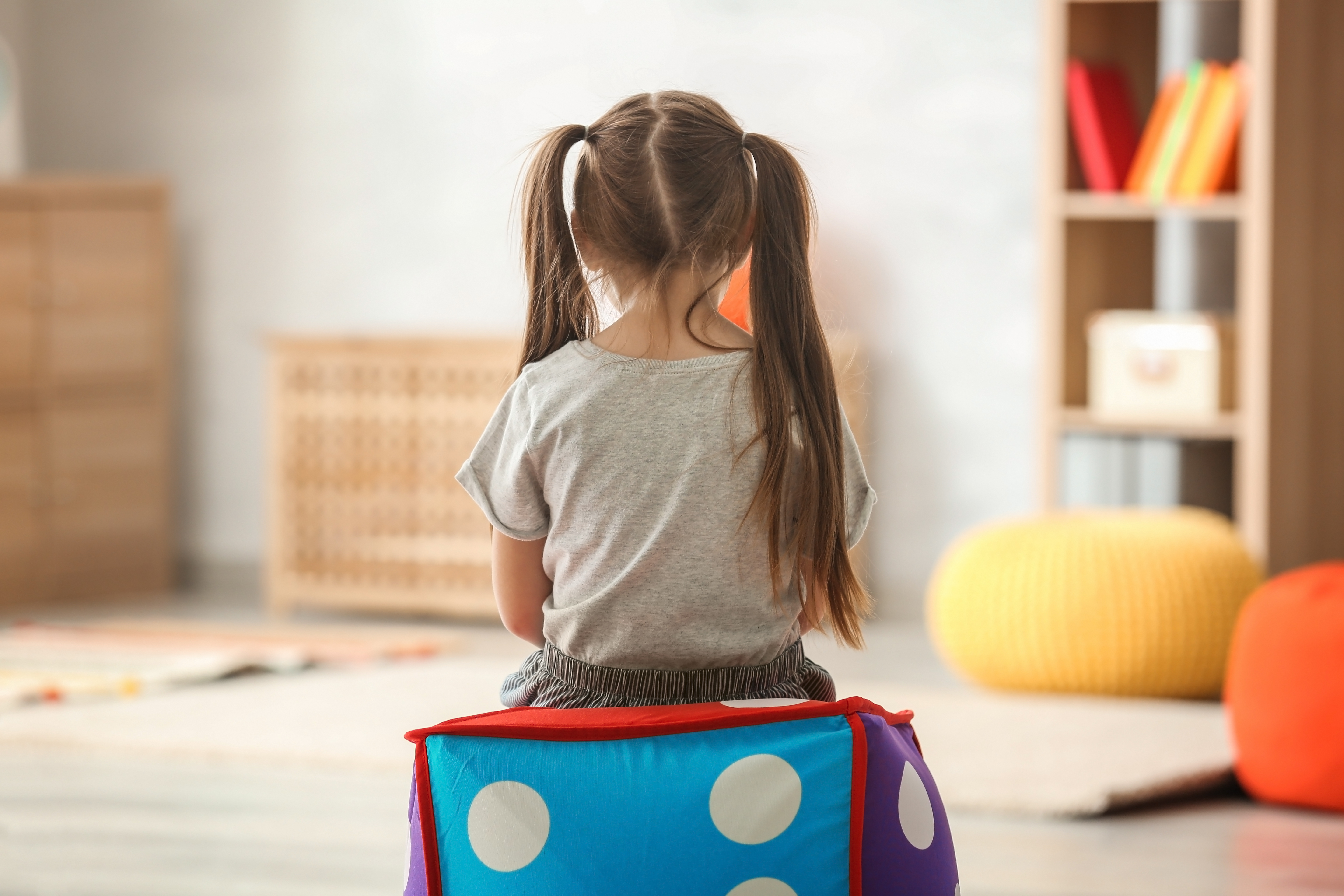 Ένα παιδί, με την πλάτη στην κάμερα, κάθεται σε ένα πολύχρωμο πολυθρονάκη 
