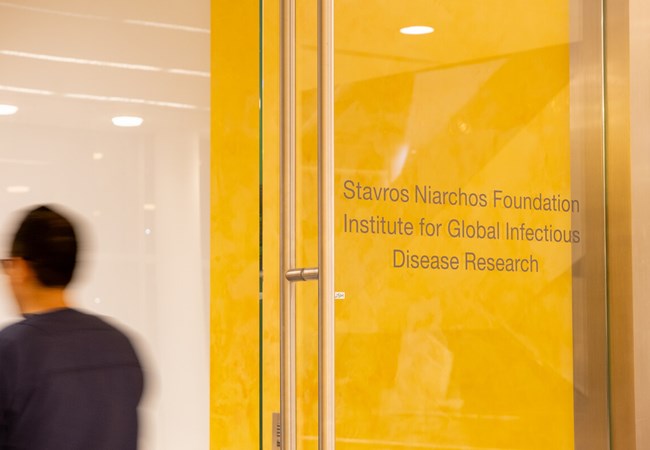 Μια γυάλινη πόρτα μπροστά από έναν κίτρινο τοίχο  που γράφει "Stavros Niarchos Foundation Institute for Global Infectious Disease Research"