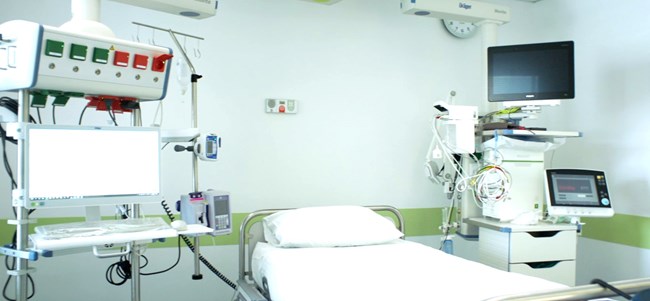 Ένα νοσοκομειακό κρεβάτι, οθόνες και ιατρικός εξοπλισμός σε ένα δωμάτιο νοσοκομείου 